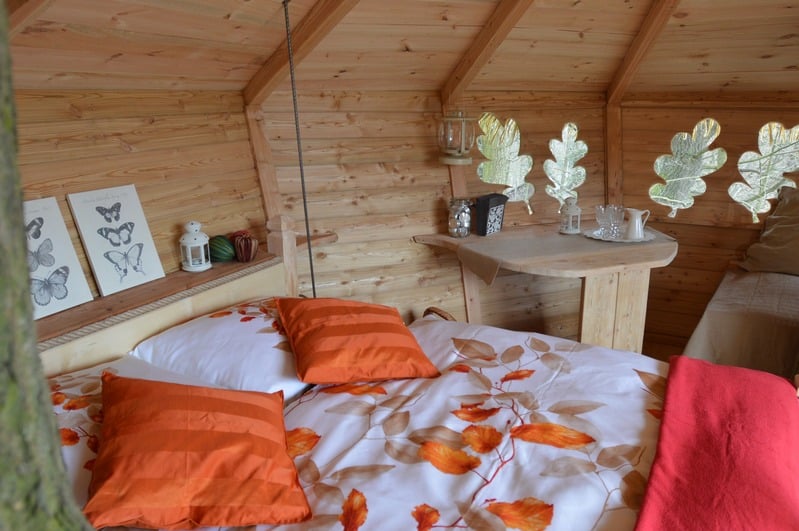 Útulný dřevěný interiér treehousu s lůžkem
